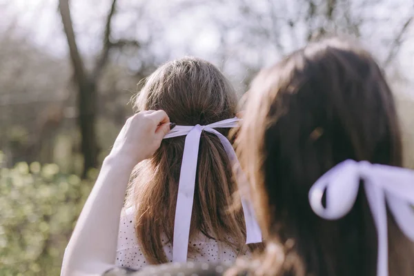 Porträt zweier hübscher junger Schwestern im grünen Frühlingsgarten, die sich auf dem Feld in der Sonne umarmen. Gemeinsam Spaß haben, positive Emotionen, bunte Farben. Kopierraum. glückliche Freundinnen bei Sonnenuntergang — Stockfoto