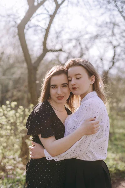 Portrait of two beautiful young sisters in the green spring gard — Stock Photo, Image