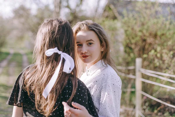 Zwei schöne junge brünette Mädchen, eines mit einem Rücken, und das andere umarmt sie im Frühlingspark. Gemeinsam Spaß haben, positive Emotionen, bunte Farben. Kopierraum. Glückliche Freundinnen — Stockfoto