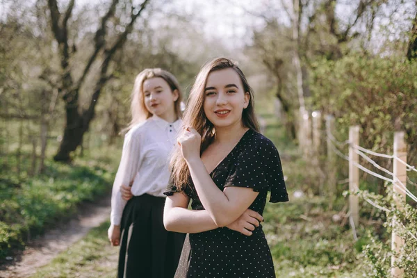 Portrét dvou krásných mladých sester v zelené jarní gardu — Stock fotografie