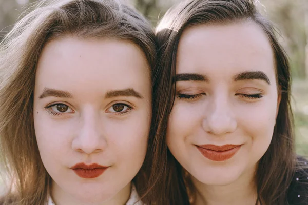 Portrét dvou krásných mladých sester v zelené jarní gardu — Stock fotografie