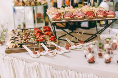 Pişmiş yemek atıştırmalıkları, sandviç, kek, bardak ve tabak, self servis, açık büfe akşam yemeği, yatay görünüm ile catering ziyafet masası
