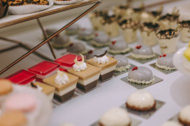 Güzel dekore edilmiş yemek masası. Hamburger, profiterol, salata ve soğuk atıştırmalıklarla. Masada çeşitli lezzetli atıştırmalıklar var.