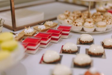 Güzel dekore edilmiş yemek masası. Hamburger, profiterol, salata ve soğuk atıştırmalıklarla. Masada çeşitli lezzetli atıştırmalıklar var.