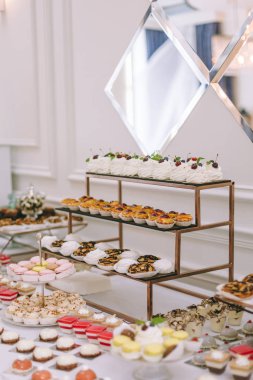 Güzel dekore edilmiş yemek masası. Hamburger, profiterol, salata ve soğuk atıştırmalıklarla. Masada çeşitli lezzetli atıştırmalıklar var.