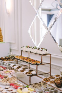 Güzel dekore edilmiş yemek masası. Hamburger, profiterol, salata ve soğuk atıştırmalıklarla. Masada çeşitli lezzetli atıştırmalıklar var.