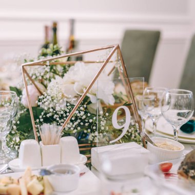 Dokuz numaralı masa. düğün masasına. tedavi tablo. Dekor. düğün detayları. Yuvarlak ziyafet masası servis edilir. Düğün yemeği için Restoran İç, misafirler için hazır. Çiçekli aranjman ile dekore edilmiş.