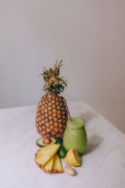 Beyaz bir masada limon, zencefil, avokado, salatalık ile yapılan ev yapımı ananas Smoothie