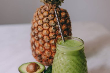 Beyaz bir masada limon, zencefil, avokado, salatalık ile yapılan ev yapımı ananas Smoothie