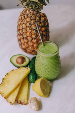 Beyaz bir masada limon, zencefil, avokado, salatalık ile yapılan ev yapımı ananas Smoothie