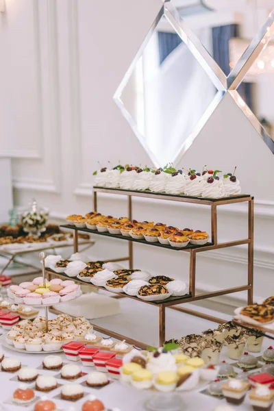 Güzel dekore edilmiş yemek masası. Hamburger, profiterol, salata ve soğuk atıştırmalıklarla. Masada çeşitli lezzetli atıştırmalıklar var.