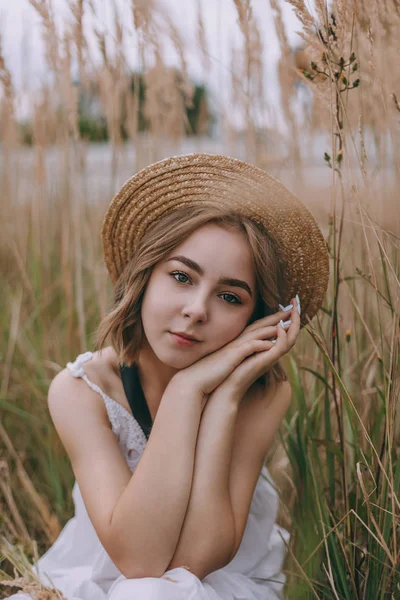Schönes Mädchen auf einem Feld sitzend. attraktive junge Frau im weißen Bohème-Kleid mit windigen Haaren, die es sich zwischen Blättern gemütlich macht. Sommerferien — Stockfoto