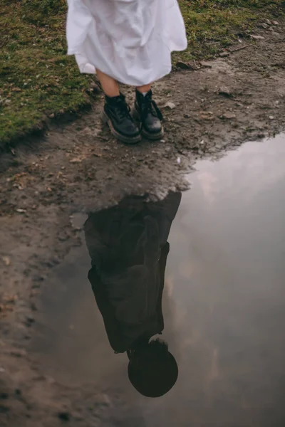 Flicka i en vit klänning berör hennes reflektion i sjön — Stockfoto