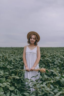 kurutulmuş otlar buketsarılma yeşil alanda beyaz elbise ve hasır şapka güzel genç kız