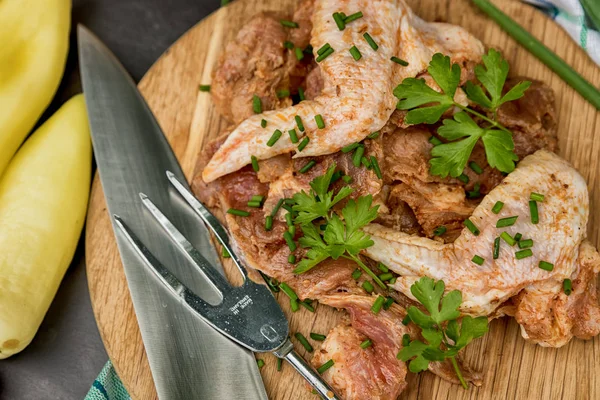 marinated raw chicken wings ready for grilling on a dark background. Raw chicken wings and vegetables