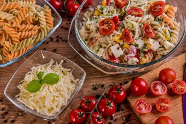 Lezzetli makarna salatası veya Akdeniz salatası. Domates mozzarella fesleğen Mısır baharat ve zeytinyağı ahşap bir masa üzerinde. Geleneksel İtalyan yemekleri