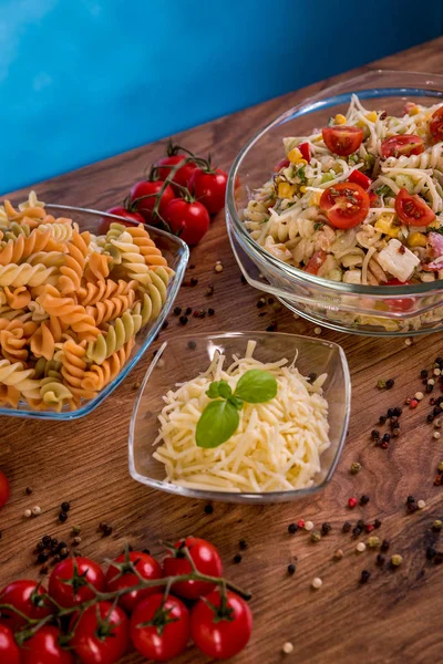 Lezzetli makarna salatası veya Akdeniz salatası. Domates mozzarella fesleğen Mısır baharat ve zeytinyağı ahşap bir masa üzerinde. Geleneksel İtalyan yemekleri