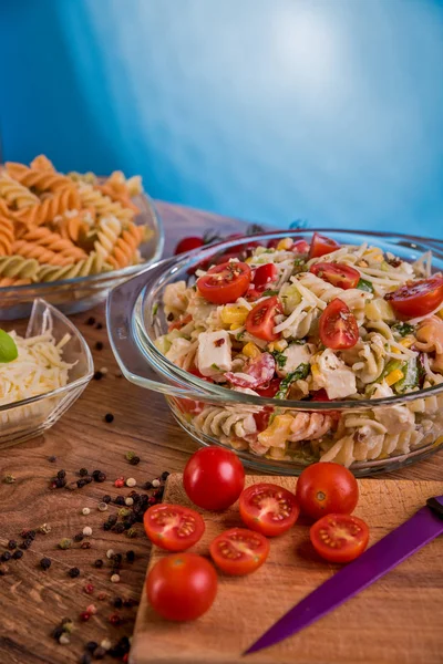 Delicious pasta salad or Mediterranean salad. Tomatoes mozzarella basil corn spice and olive oil on a wooden table. Traditional Italian food