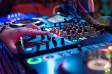 Müzikal etkinlikler için profesyonel ses mikseri. Eller arka plan renkli ışık atmosfer Dj operatörü