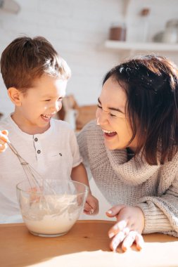 Anne ve oğlu parlak bir mutfağın arka planında yemek pişiriyorlar. Çocuk ebeveynlerin kendi kendini izole etme koşullarında hamur yoğurmasına yardım eder. Aptallık yapmak parayla kirlenir..