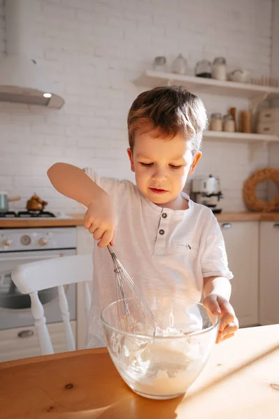 A Boy In The Background Of A Bright Kitchen Kneads A Dough For Baking In A Glass Dish A Child Helps Mom Cook Little Working Stock Photo 378633740