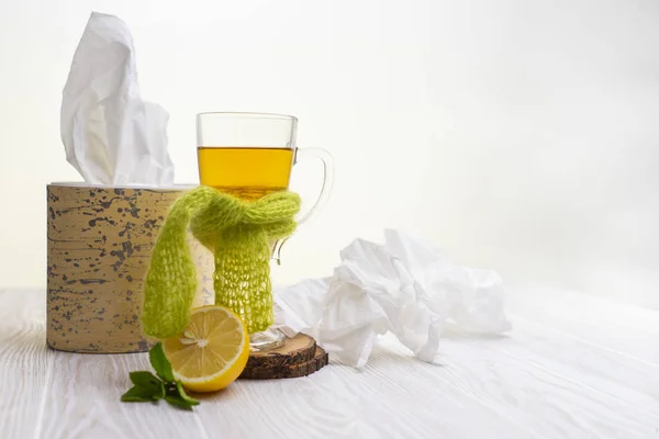 yeşil bir eşarp ve mendil ile yüksek bir cam kupa bitkisel limon çayı