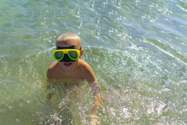 Denizde maskeli yüzmenin keyfini çıkaran çocuk