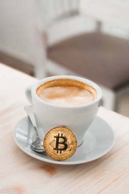 Kahve fincanı cryptocurrency altın bitcoin ayakta. Altın cryptocurrency ve beyaz yumuşak zemin üzerine sıcak kahve kupa bardak. 