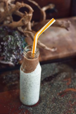 Çikolata muz smoothie eski ahşap rustik arka plan üzerinde bir cam kavanoza Chia pudingle. Sağlıklı vejetaryen kahvaltı yoğurt kefir chia tohum ile. Seçilen odak, dikey, kopyalama alanı