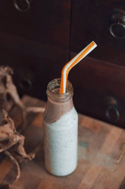 Çikolata muz smoothie eski ahşap rustik arka plan üzerinde bir cam kavanoza Chia pudingle. Sağlıklı vejetaryen kahvaltı yoğurt kefir chia tohum ile. Seçilen odak, dikey, kopyalama alanı