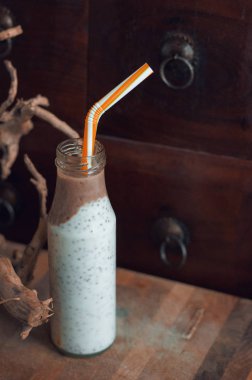 Çikolata muz smoothie eski ahşap rustik arka plan üzerinde bir cam kavanoza Chia pudingle. Sağlıklı vejetaryen kahvaltı yoğurt kefir chia tohum ile. Seçilen odak, dikey, kopyalama alanı