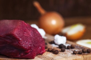 Çiğ domuz biftek ile ahşap tahta ve tuz, biber. Ahşap zemin, üstten görünüm Aromatik baharatlar ile taze Dana biftek. Sağlıklı yemek pişirme işlemi.