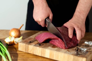 Erkek Şef domuz eti yemek pişirmek için hazırlanıyor. Pişirme biftek et dostum. Ahşap masa, üstten görünüm sığır eti yemek için ham maddeler. Kopya alanı ile beyaz backgroung.