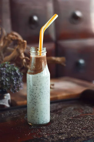Çikolata muz smoothie eski ahşap rustik arka plan üzerinde bir cam kavanoza Chia pudingle. Sağlıklı vejetaryen kahvaltı yoğurt kefir chia tohum ile. Seçilen odak, dikey, kopyalama alanı