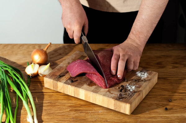 Male chef preparing pork for cooking. Man cooking beef meat. Raw ingredients for cooking beef meat on wooden table, top view. White backgroung with copy space.