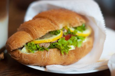 Taze kruvasan ton balığı, limon ve salata ahşap arka plan üzerinde. Kahvaltı konsepti.