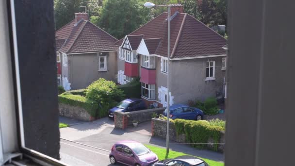 Single pedestrians walking on the street by houses and traffic on a nice day. — Stock Video