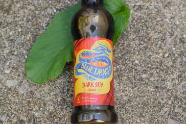 Gri arkaplanda renkli etiketli soya sosu şişesi..