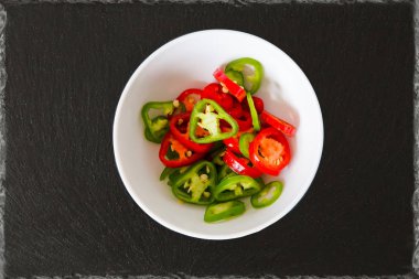 biber yeşil kırmızı siyah arduvaz arka plan yuvarlak kase ile kesmek