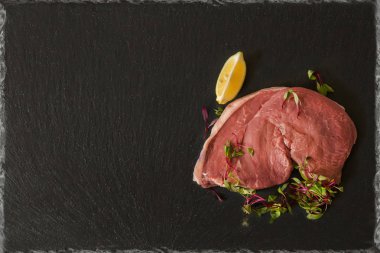 ham serbest gezinen kıç biftek beef limon dilimi ve mikro salata garnitür ile siyah arduvaz tabakta