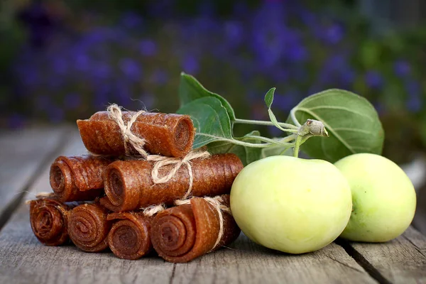 Handmade twisted apple pastille tied with linen thread on a wooden background with apples