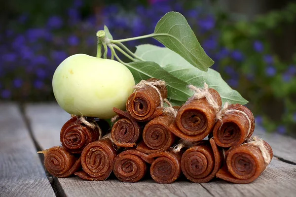 Handmade twisted apple pastille tied with linen thread on a wooden background with apples