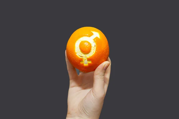 Gender equality. Orange with the sign of gender equality in the hand of a woman. Chalk Board background