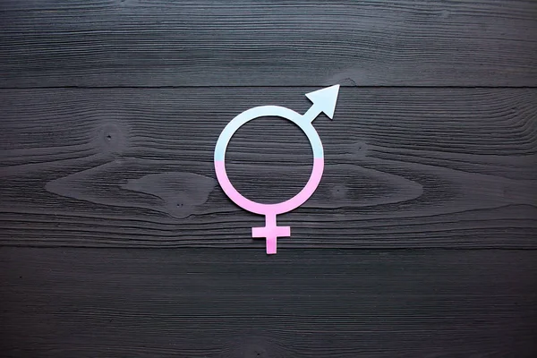 Female gender symbol of equality male, the concept of gender equality. Black wooden background. A paper-cut symbol of gender equality. Unique texture.