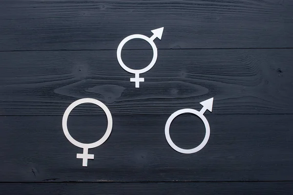 The female gender symbol, gender symbol for men and symbol of gender equality, the concept of gender equality. Black wooden background. A paper-cut symbol of gender equality. Unique texture.