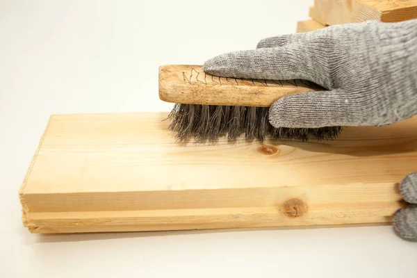 Hand wire brush men\'s hands in protective gloves on vintage wooden Board. Aging wooden boards by brushing. White background. Create fotofone