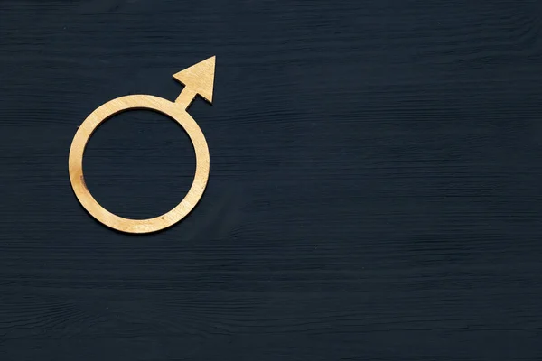 A symbol of gender equality made of plywood. Black wooden background. Male and female symbols