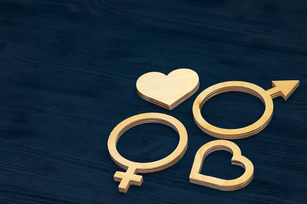 A symbol of gender equality made of plywood. Black wooden background. Male and female symbols