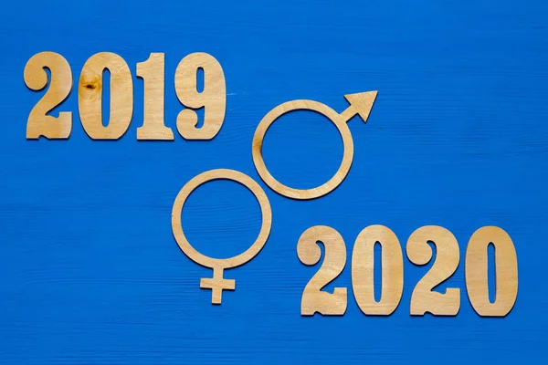 Symbol of men and women. Symbol of gender equality. 2019 - 2020. The characters are cut out of plywood. Blue wooden background.