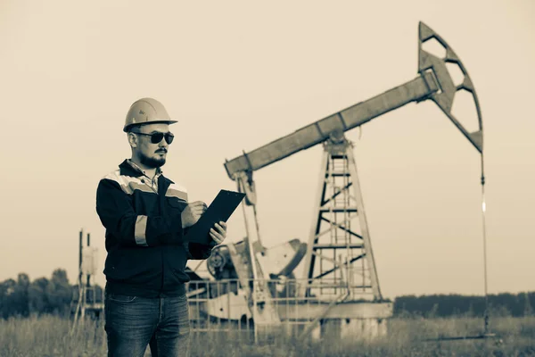 A worker with a tablet monitors the serviceability of oil pumps